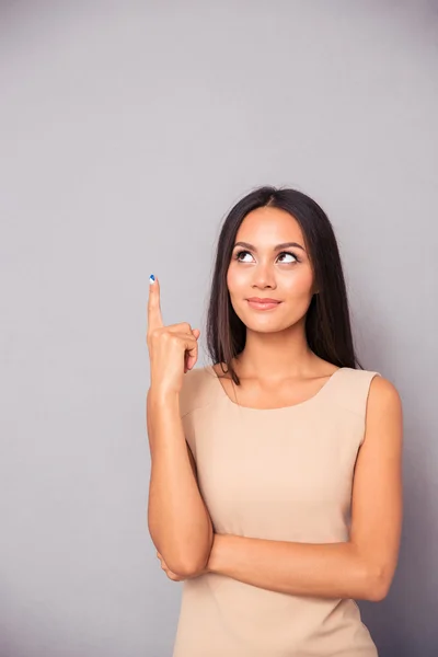 Nachdenkliche junge Frau zeigt mit dem Finger nach oben — Stockfoto