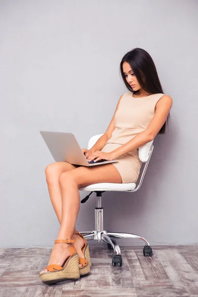 Mulher usando laptop no fundo cinza — Fotografia de Stock