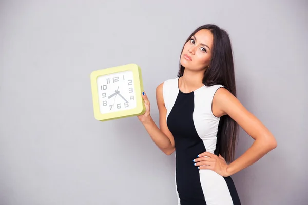 Portrait of a tired woman holding clock — Stock Photo, Image