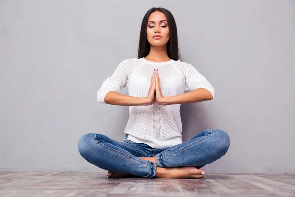 Žena v džínách, meditovat na podlaze — Stock fotografie