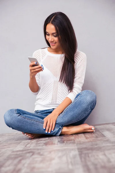 Frau sitzt auf dem Boden und benutzt Smartphone — Stockfoto