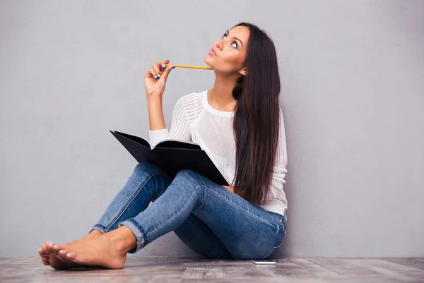 Girl sitting on the floor with notepad and pencil — Stock Photo, Image