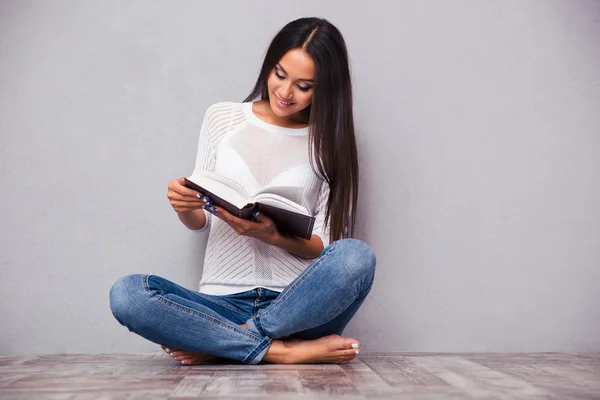 Flickan sitter på golvet och läser bok — Stockfoto