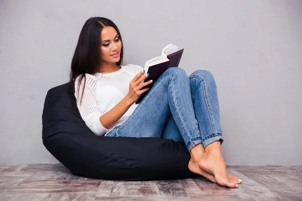 Kobieta siedzi na krześle worek i czytanie książki o — Zdjęcie stockowe