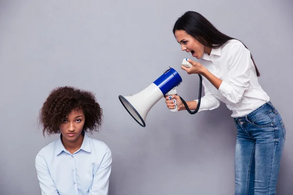 Woman shouting through loudspaker on her friend — Stock Photo, Image