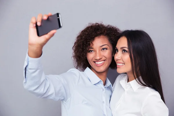 Sonriendo a dos chicas haciendo foto selfie en el teléfono inteligente — Foto de Stock