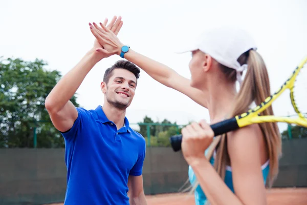 Male and female tennis players gives five
