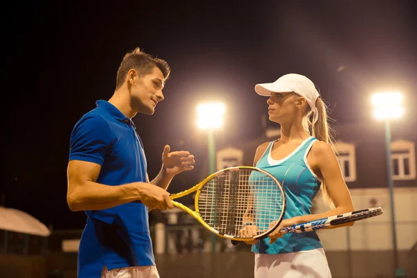 Mannelijke en vrouwelijke tennisspelers praten buiten — Stockfoto