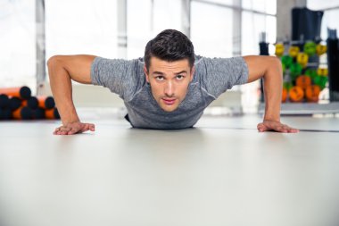 Handsome man doing push-ups in gym clipart