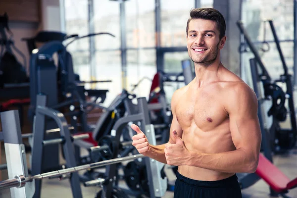 Uomo muscolare mostrando pollici in alto in palestra — Foto Stock