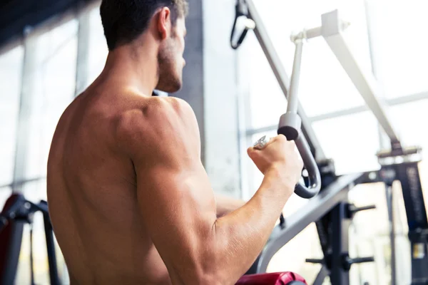 Culturista haciendo ejercicio en la máquina de fitness en el gimnasio —  Fotos de Stock