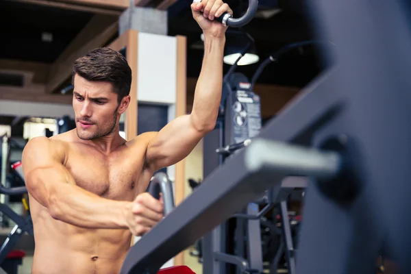 Culturista haciendo ejercicio en la máquina de fitness en el gimnasio —  Fotos de Stock