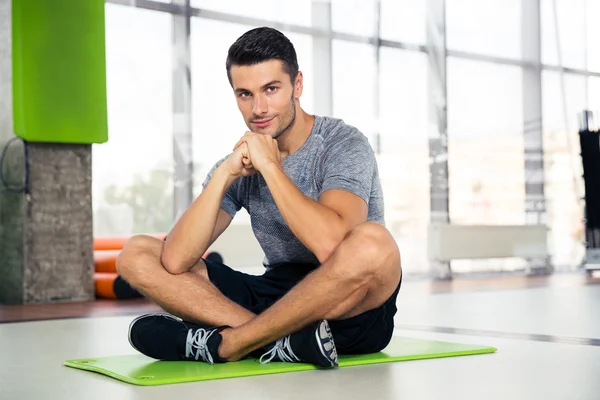 Fitness uomo seduto sul tappetino yoga in palestra — Foto Stock