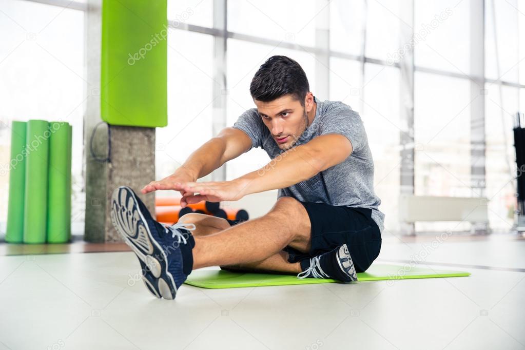 Man doing stretching exercises at gym 