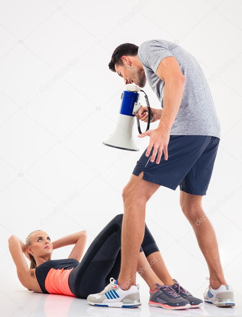 rainer shouting through megaphone on a sports woman to doing exercises