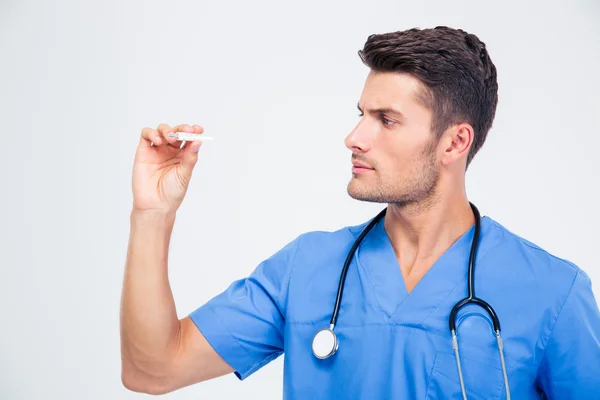Handsome male doctor looking on thermometer — Stock Photo, Image
