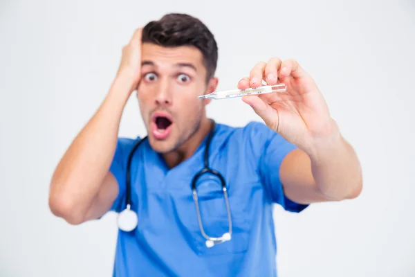 Shocked male doctor holding thermometer — Stock Photo, Image