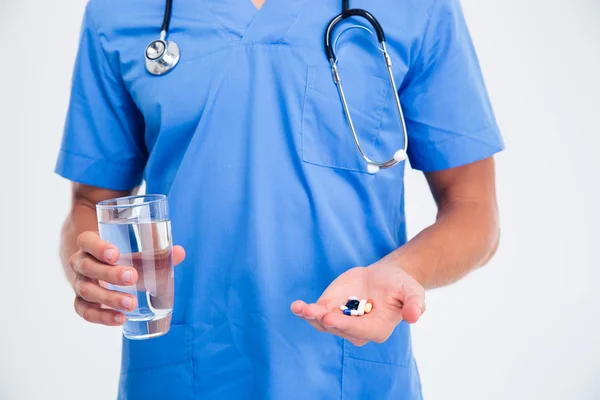 Médico masculino sosteniendo píldoras y vidrio con agua —  Fotos de Stock