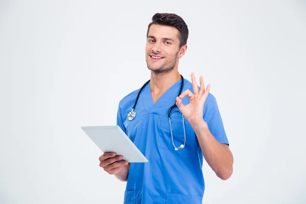 Tablet bilgisayar basılı tutup ok işaret gösteren erkek doktor — Stok fotoğraf