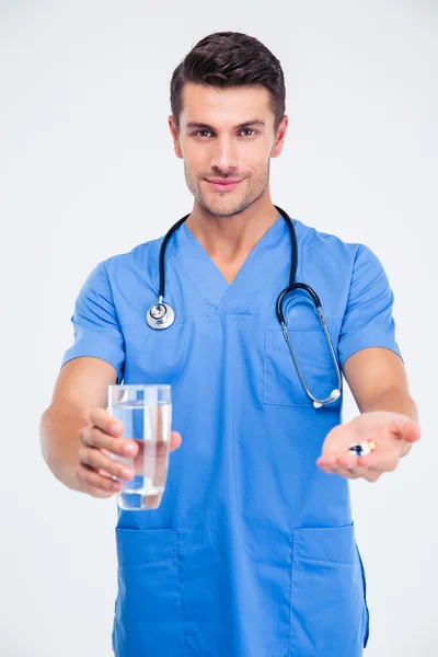 Glücklicher männlicher Arzt mit Glas mit Wasser und Pille — Stockfoto