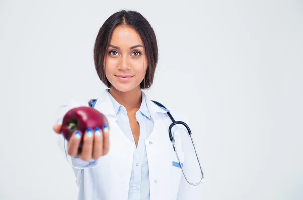 Retrato de médico bonito feminino dando maçã na câmera — Fotografia de Stock