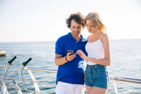 Hombre y mujer utilizando el teléfono inteligente juntos al aire libre —  Fotos de Stock