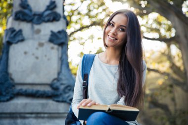 Gülümseyen kız öğrenci tutan kitap