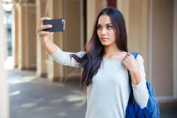 Женщина-студентка делает селфи фото на смартфоне — стоковое фото