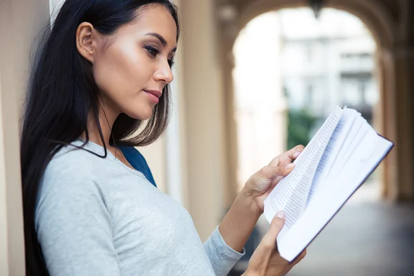 Vrouwelijke student leesboek buitenshuis — Stockfoto