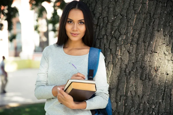 Happy kvinnlig student skriva noter i anteckningar — Stockfoto