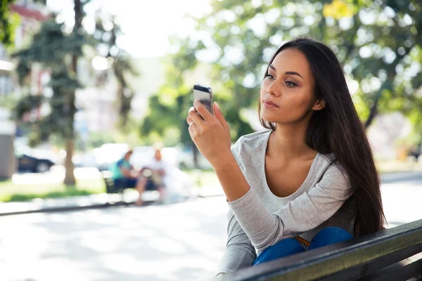 Frau nutzt Smartphone auf der Bank im Freien — Stockfoto