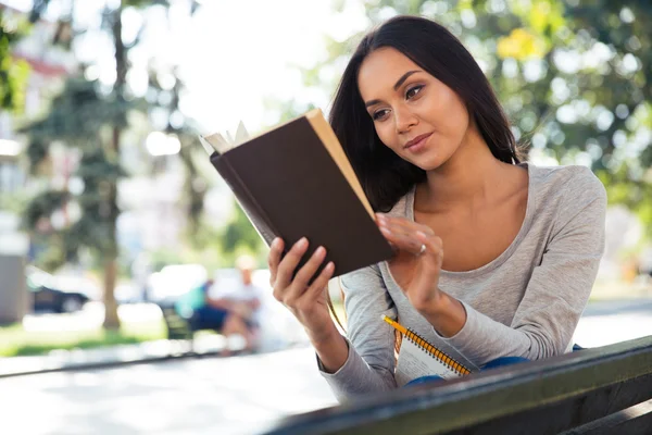 Vrouw lezen boek op de Bank buitenshuis — Stockfoto