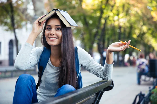 Rolig tjej håller boken på huvudet utomhus — Stockfoto