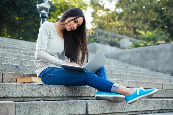 Flicka sitter i staden trappan med laptop utomhus — Stockfoto