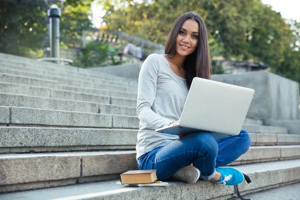 Siswa perempuan menggunakan komputer laptop di luar ruangan Stok Gambar Bebas Royalti