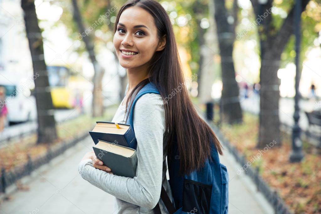 Portrait of a happy female student holding books