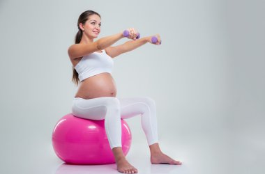 Woman doing exercises with dumbbells on a fitness ball