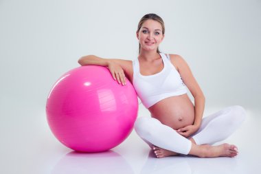 Pregnant woman sitting on the floor with fitness ball
