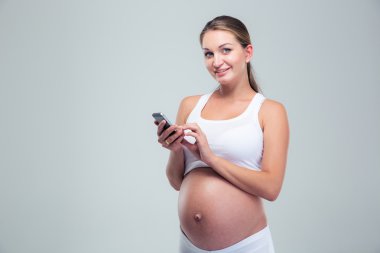 Pregnant woman using smartphone and looking at camera