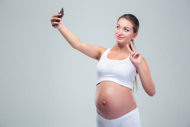 Pregnant woman making selfie photo on smartphone
