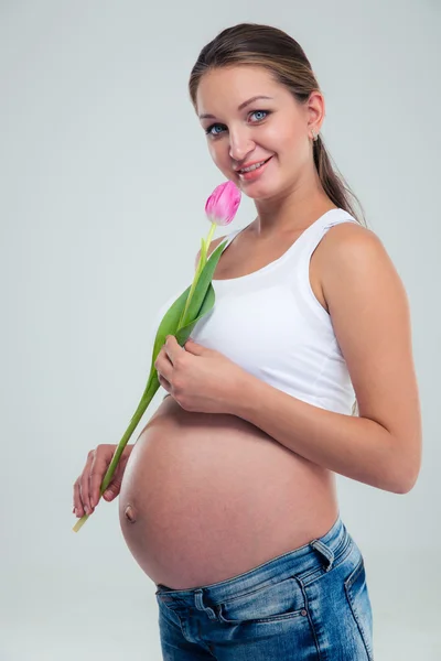 Усміхнена вагітна жінка тримає квітку — стокове фото