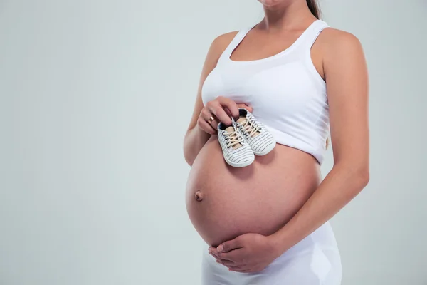 Embarazada mujer sosteniendo un bebé botines — Foto de Stock