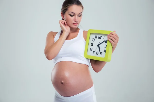 Portrait of a pregnant woman holding wall clock — Stockfoto