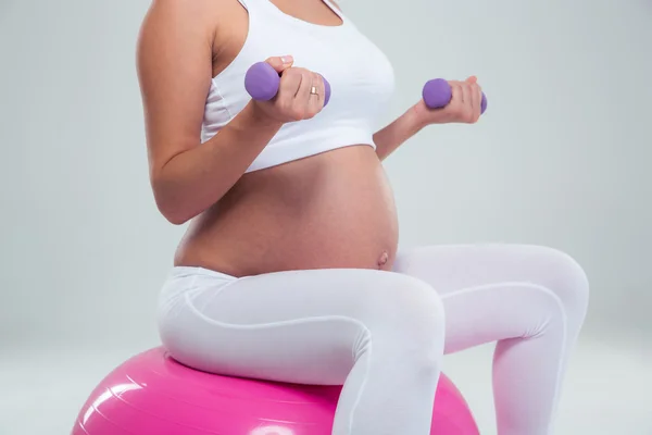 Mujer sentada en la pelota de fitness y entrenando con pesas —  Fotos de Stock