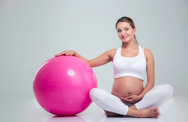 Pregnant woman sitting on the floor with fitness ball — Stok fotoğraf