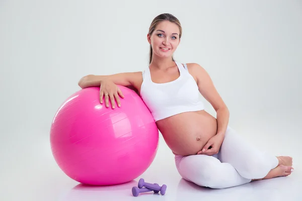 Беременная женщина сидит на полу с мячом для фитнеса — стоковое фото