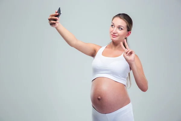 Pregnant woman making selfie photo on smartphone — Stockfoto