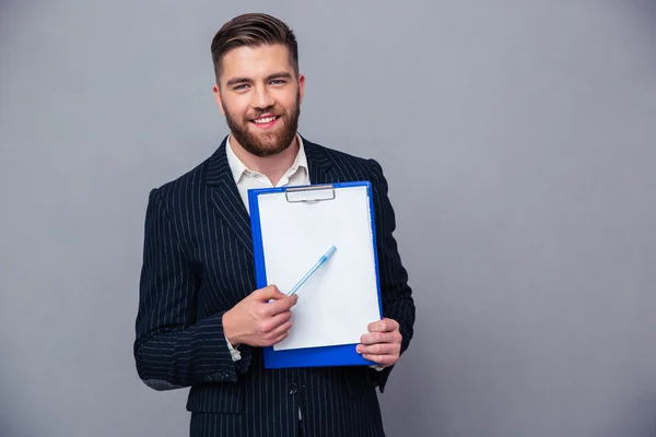 Empresário sorridente mostrando área de transferência em branco — Fotografia de Stock