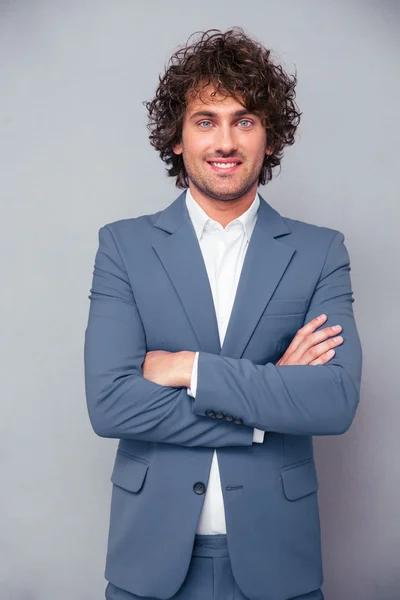 Hombre de negocios sonriente de pie con los brazos cruzados — Foto de Stock