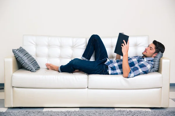 Mann liegt auf dem Sofa und liest Buch — Stockfoto